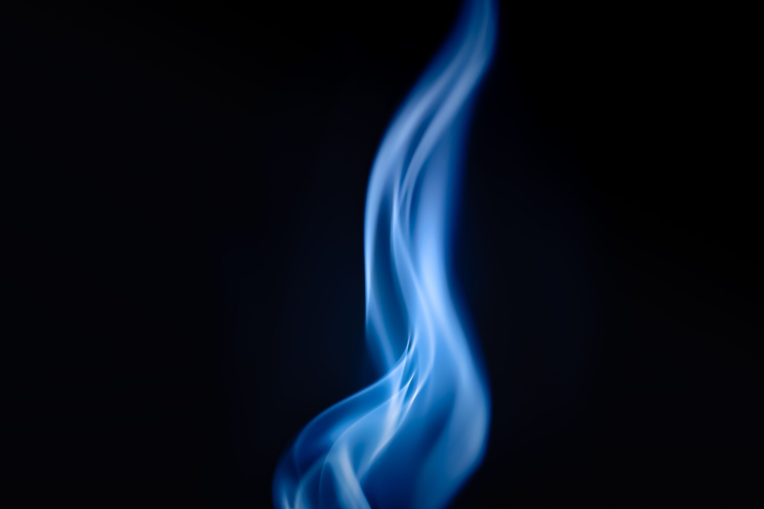 A mesmerizing abstract blue flame captured against a dark background, evoking warmth and mystery.